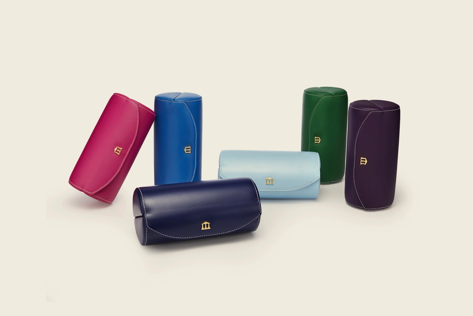 Six colorful cylindrical leather cases with gold M logos.