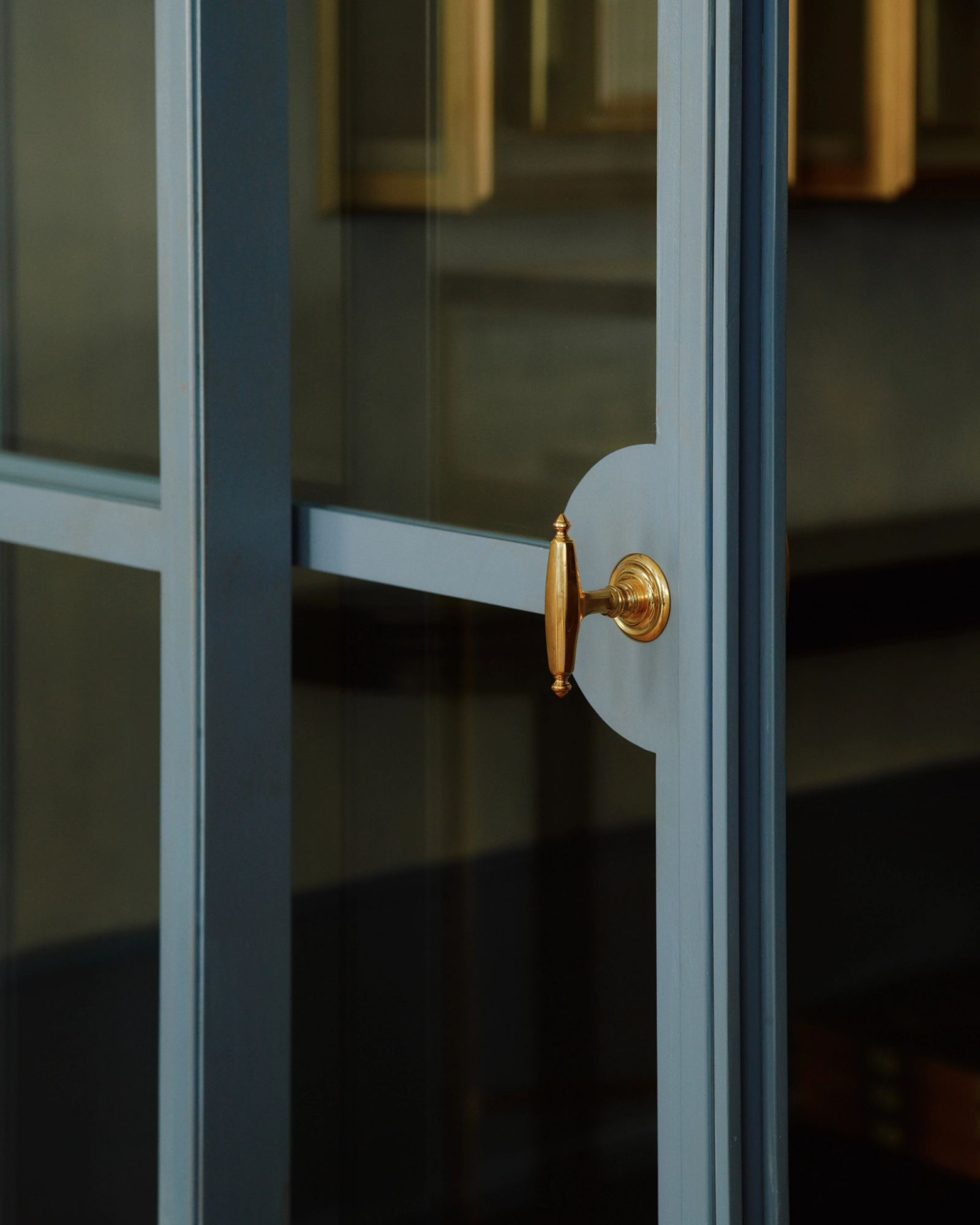 Blue-grey framed glass door with a golden handle.