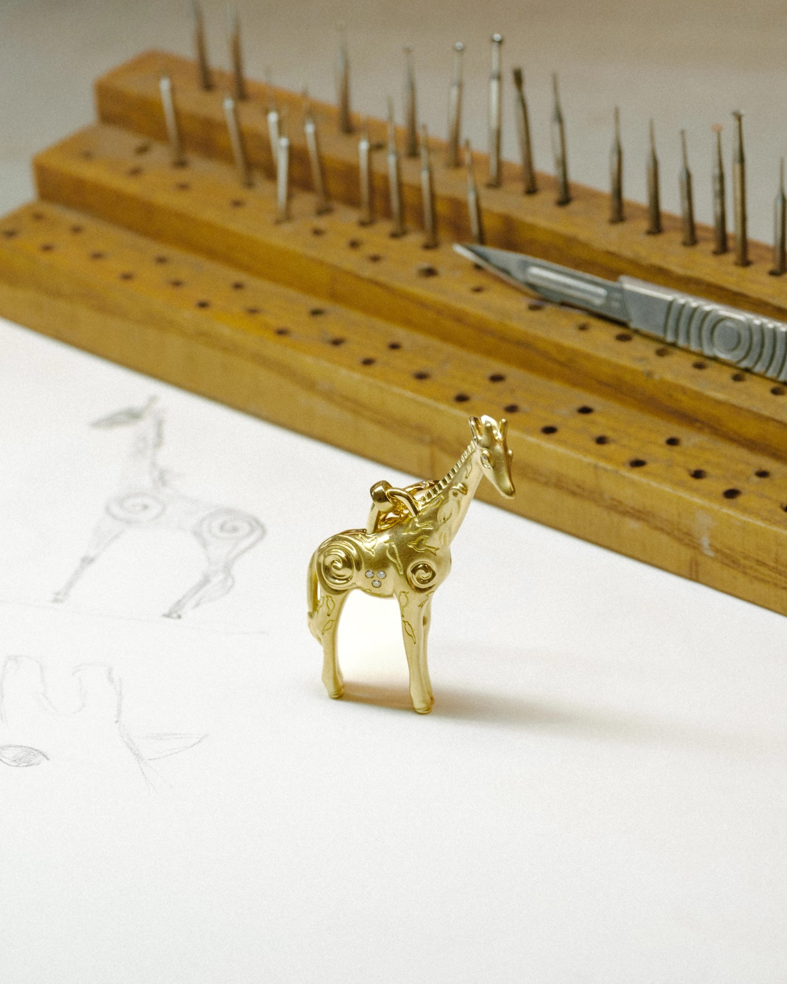 Golden horse figurine with intricate carvings and gems, next to horse sketches and crafting tools.