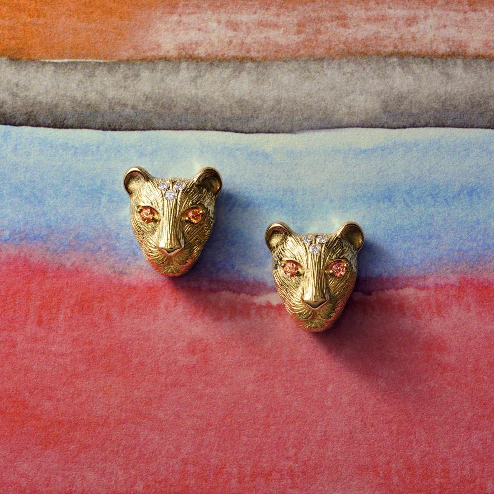 Pair of gold panther head earrings with orange gemstone eyes and diamond accents.
