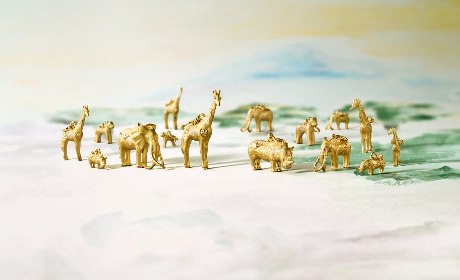Gold figurines of giraffes, elephants, and rhinos, each carrying a smaller animal, on a soft green and blue background.
