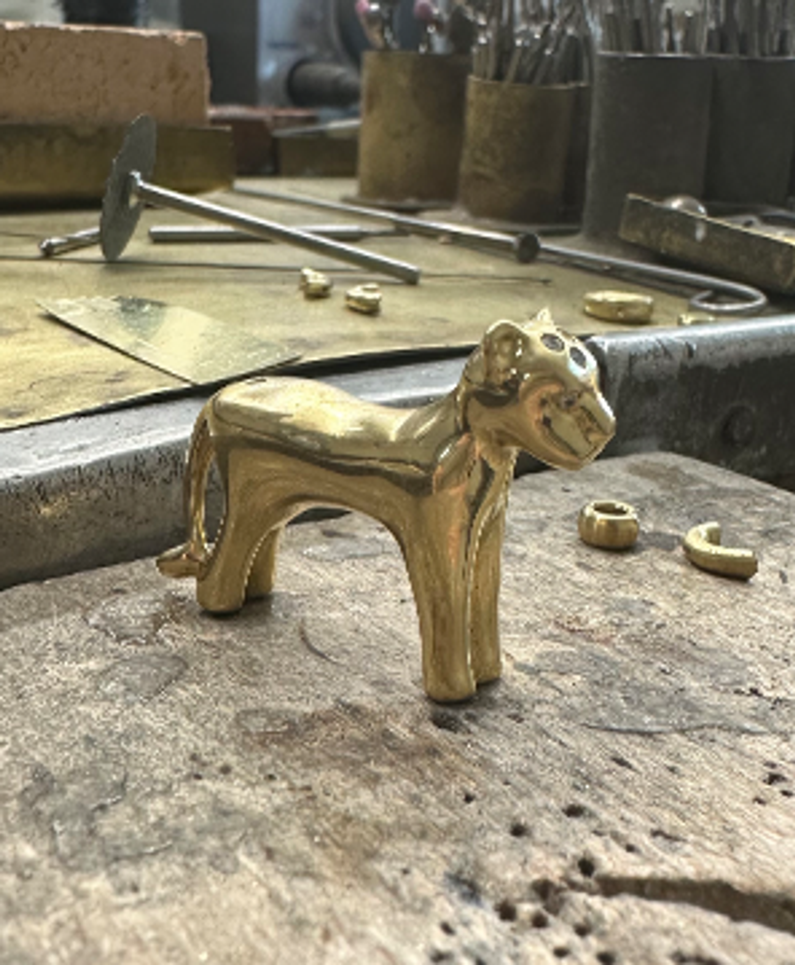 Golden jaguar figurine on a jeweler's workbench.