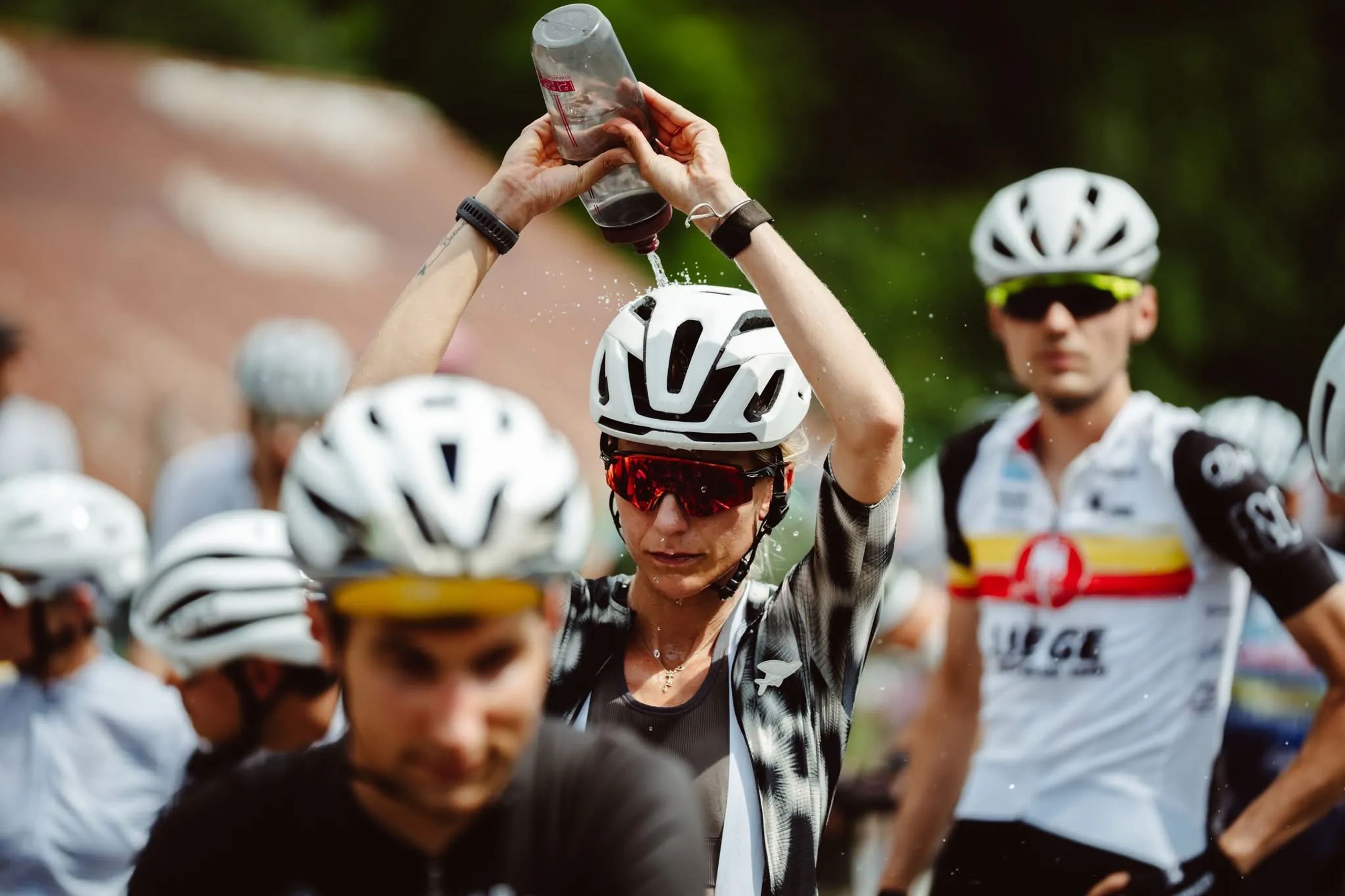 Coureuse qui s’asperge d’eau au milieu du peloton, à côté d’un coureur LGFT