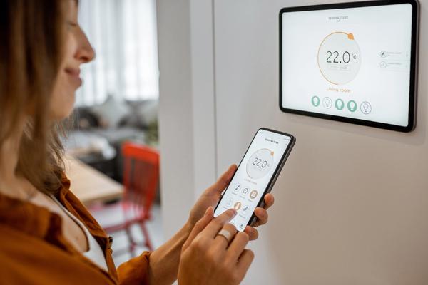 A person controlling a smart home system from a phone and wall panel