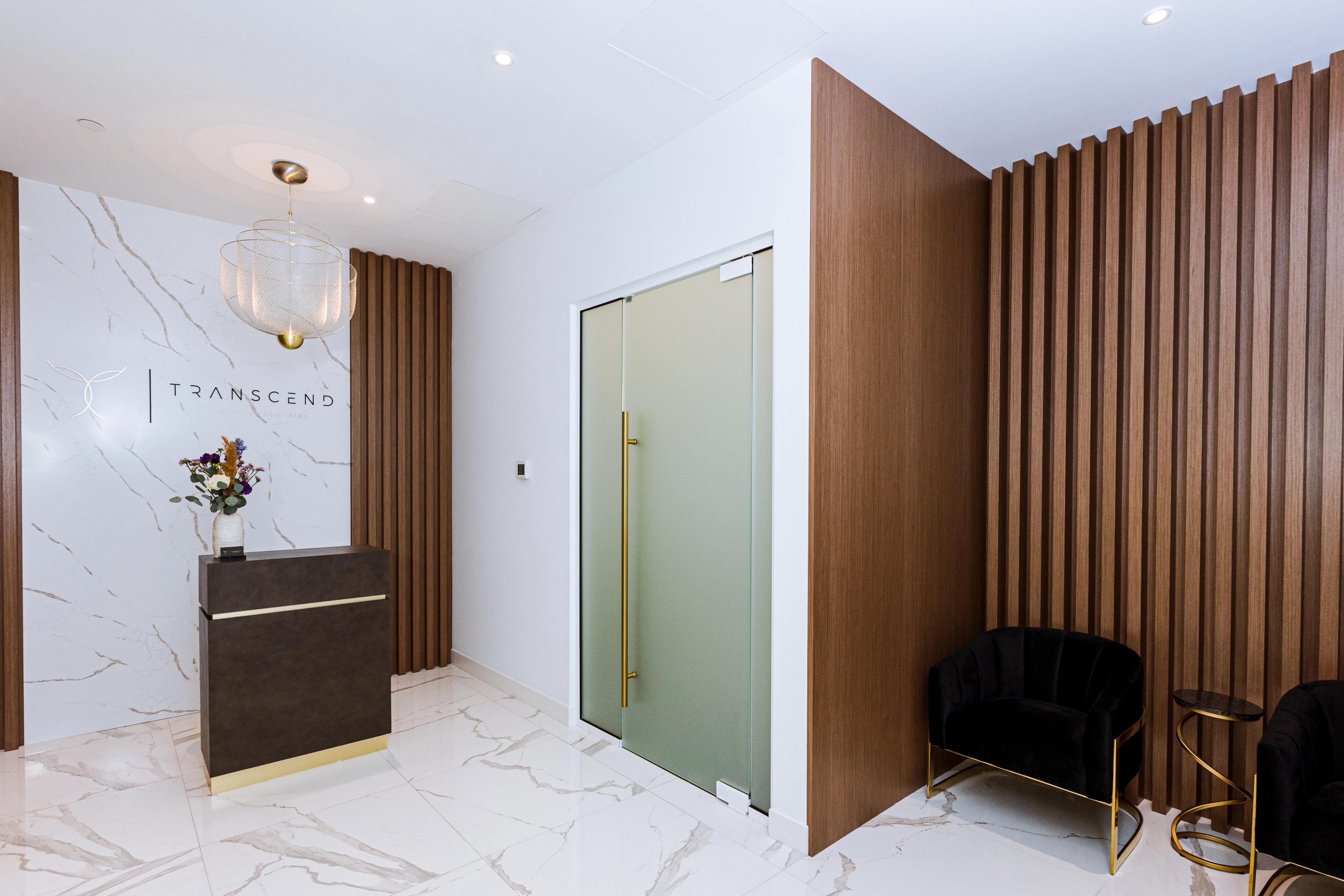 Photo of the reception and lobby of Transcend Specialized Dentistry, showing the dark wooden panels and golden accents.