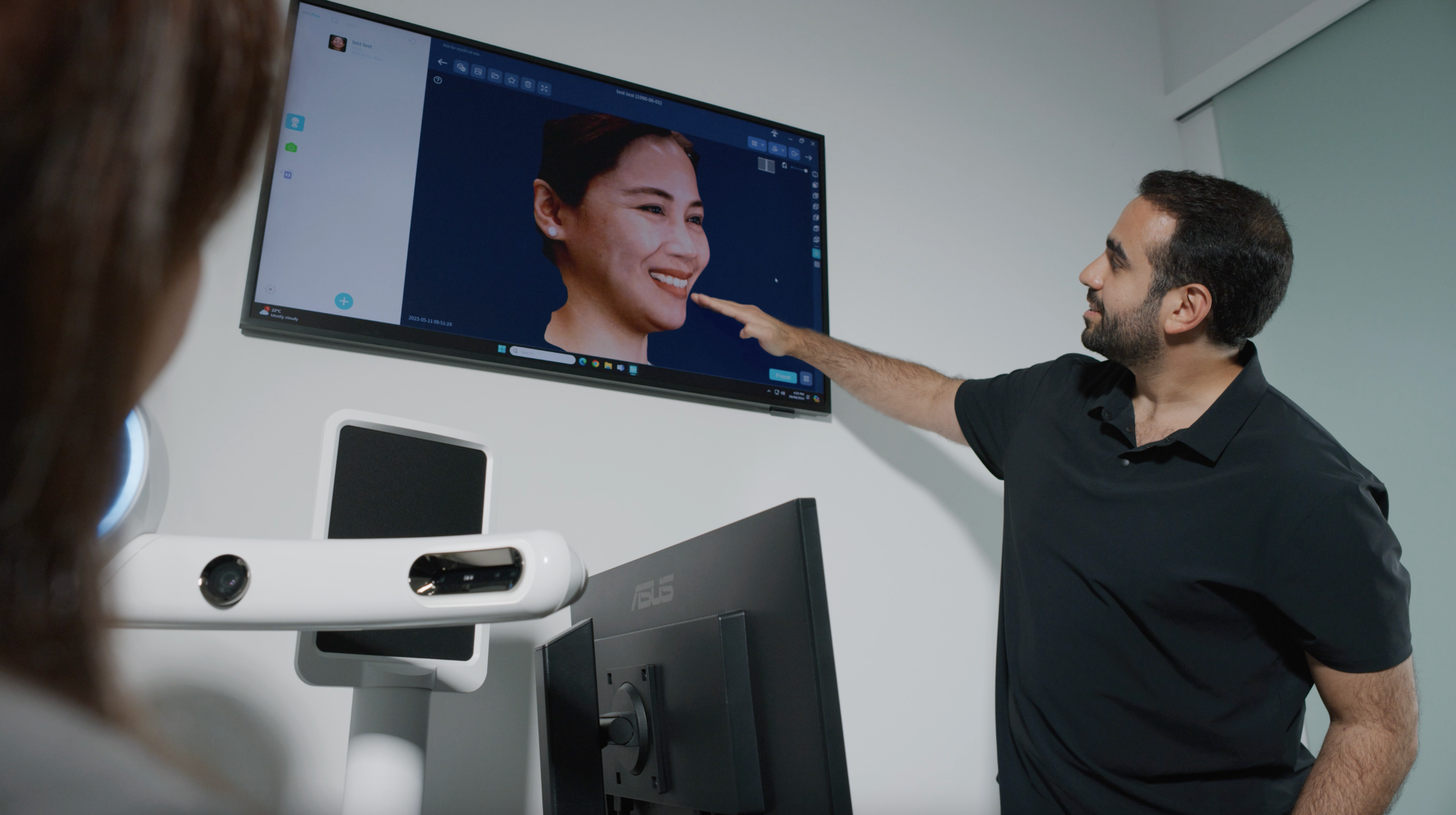Dr. Faraj Edher pointing to a television screen with a virtually-designed smile is displayed.