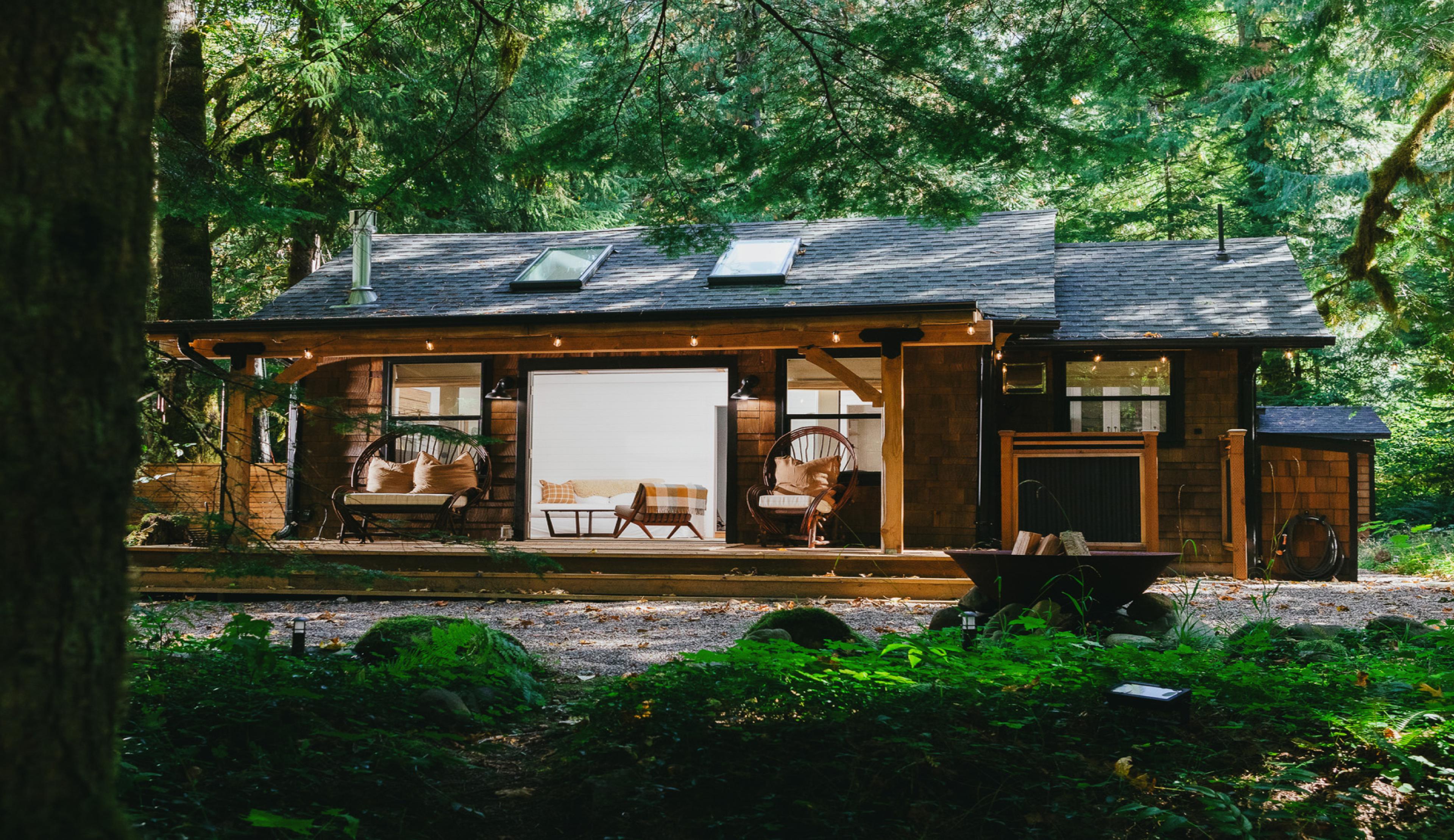 Wood cabin surrounded by forest with front door open 