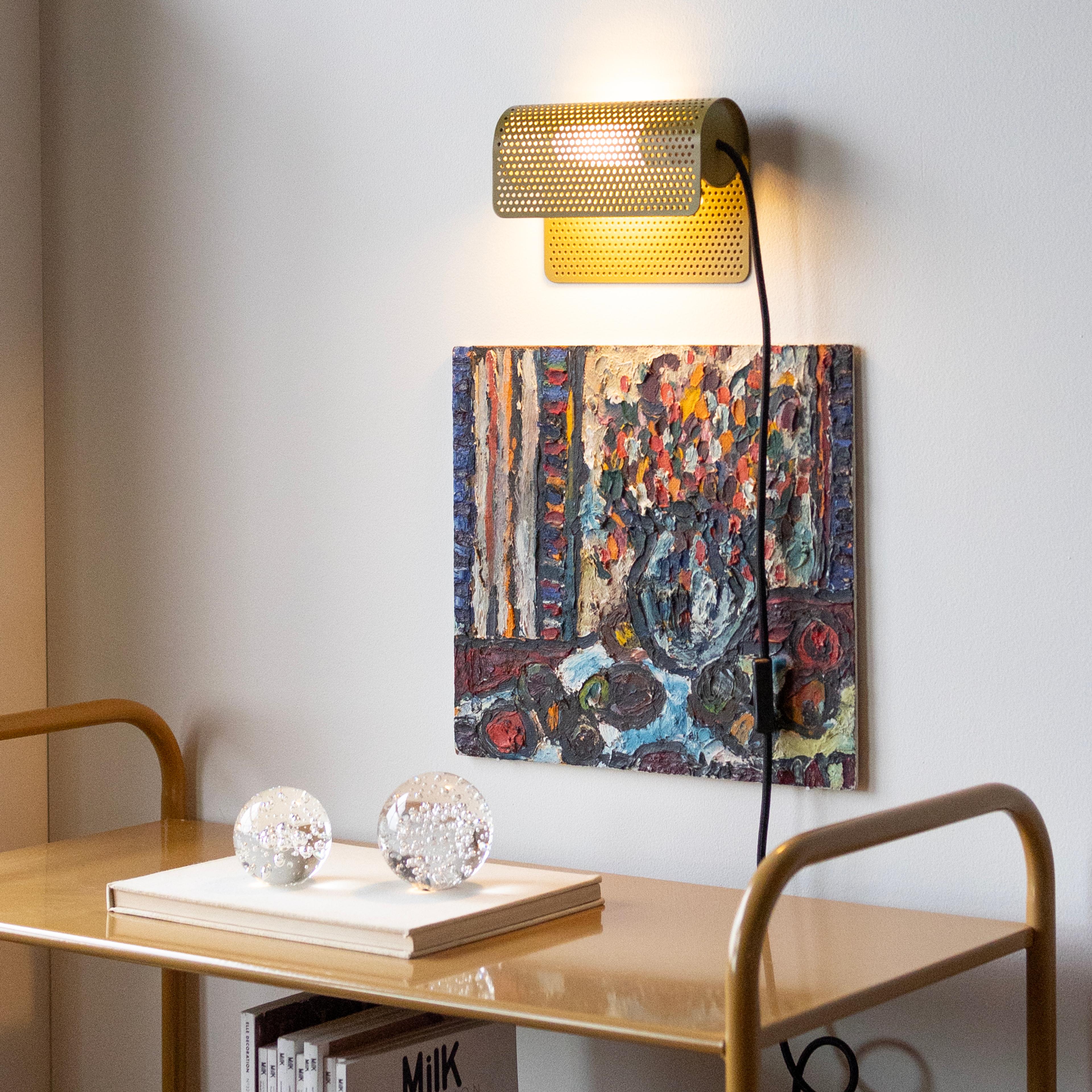 office detail of green perforated sconce above abstract painting