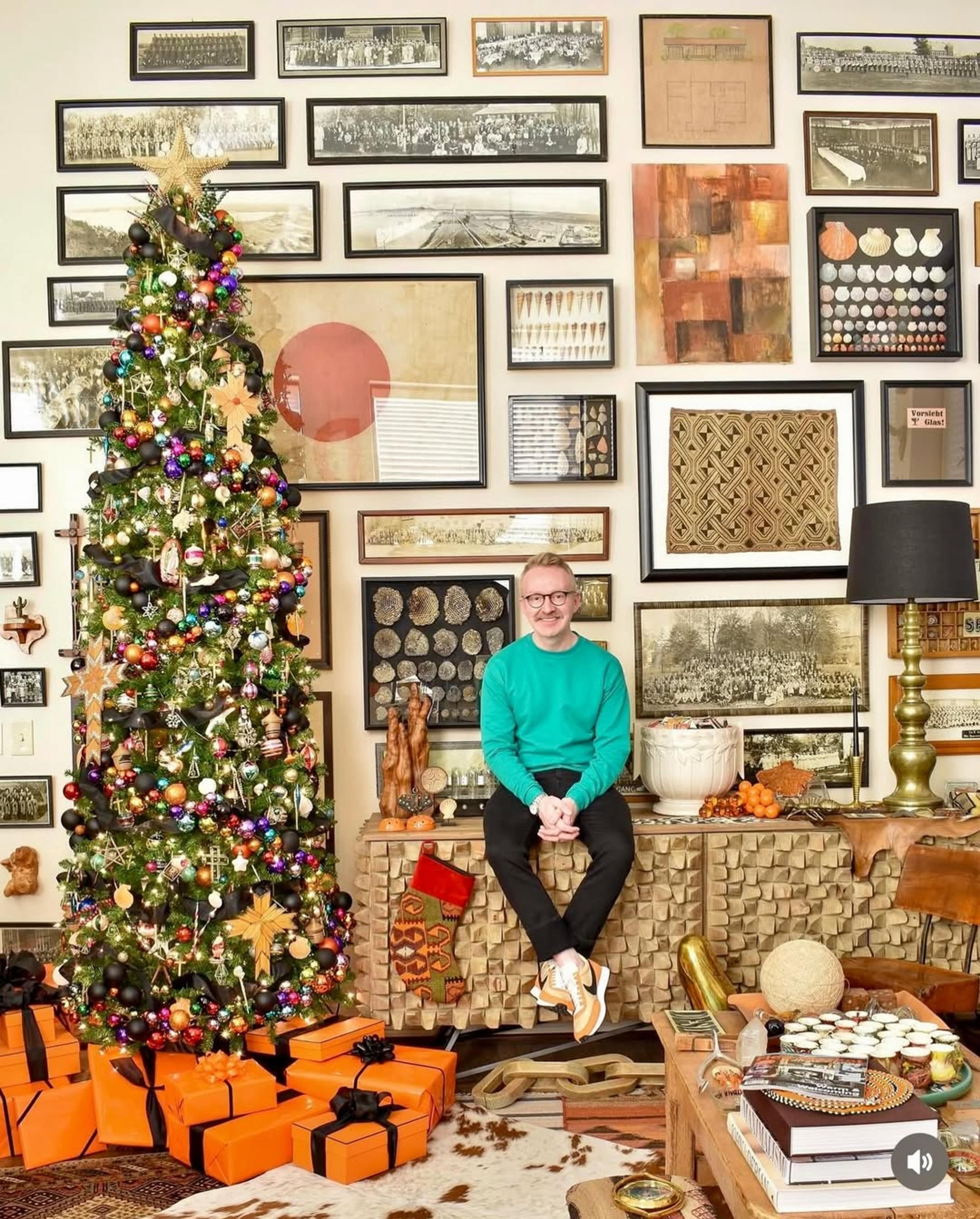 Man sitting next to Christmas tree. 