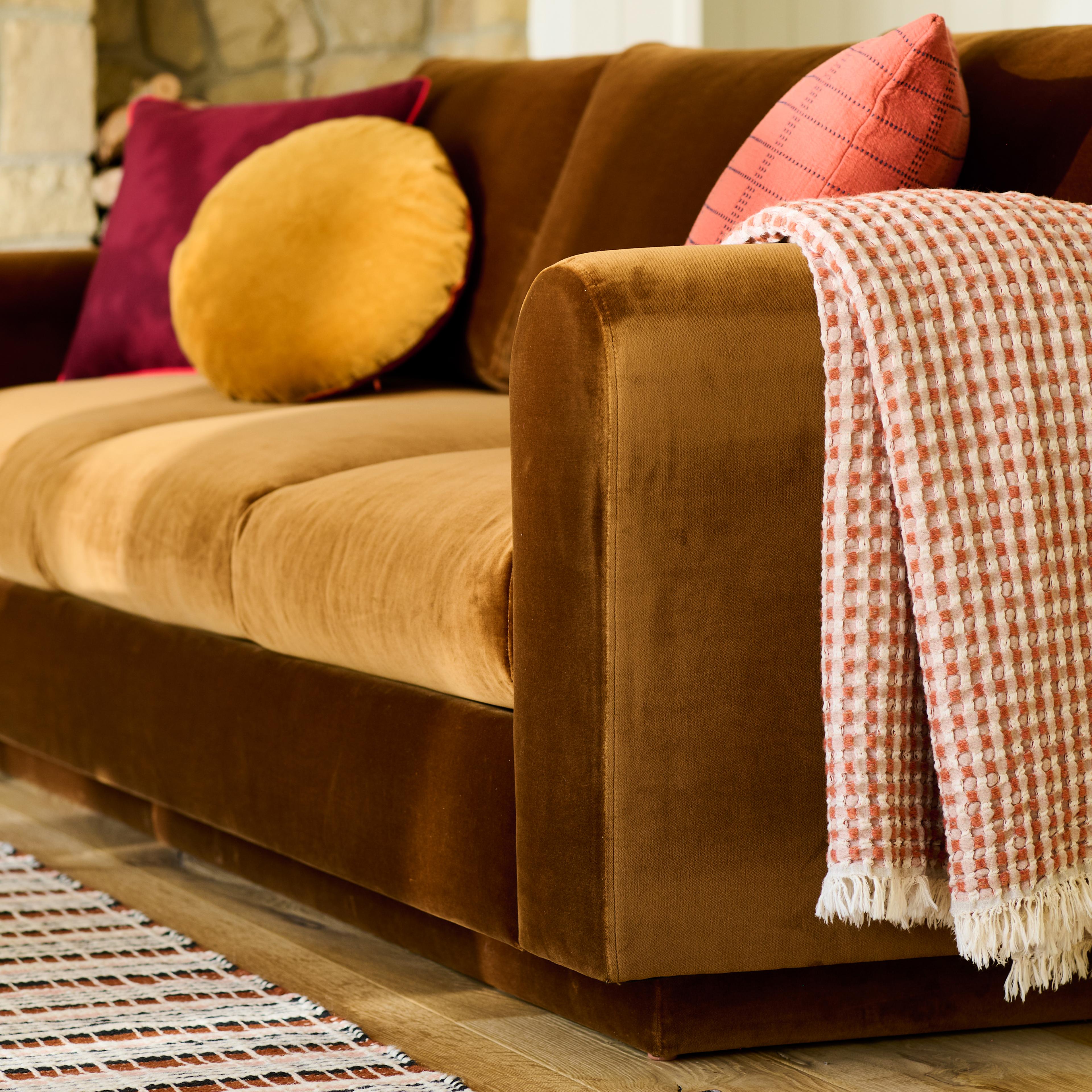 Throw draped over arm of sofa. 