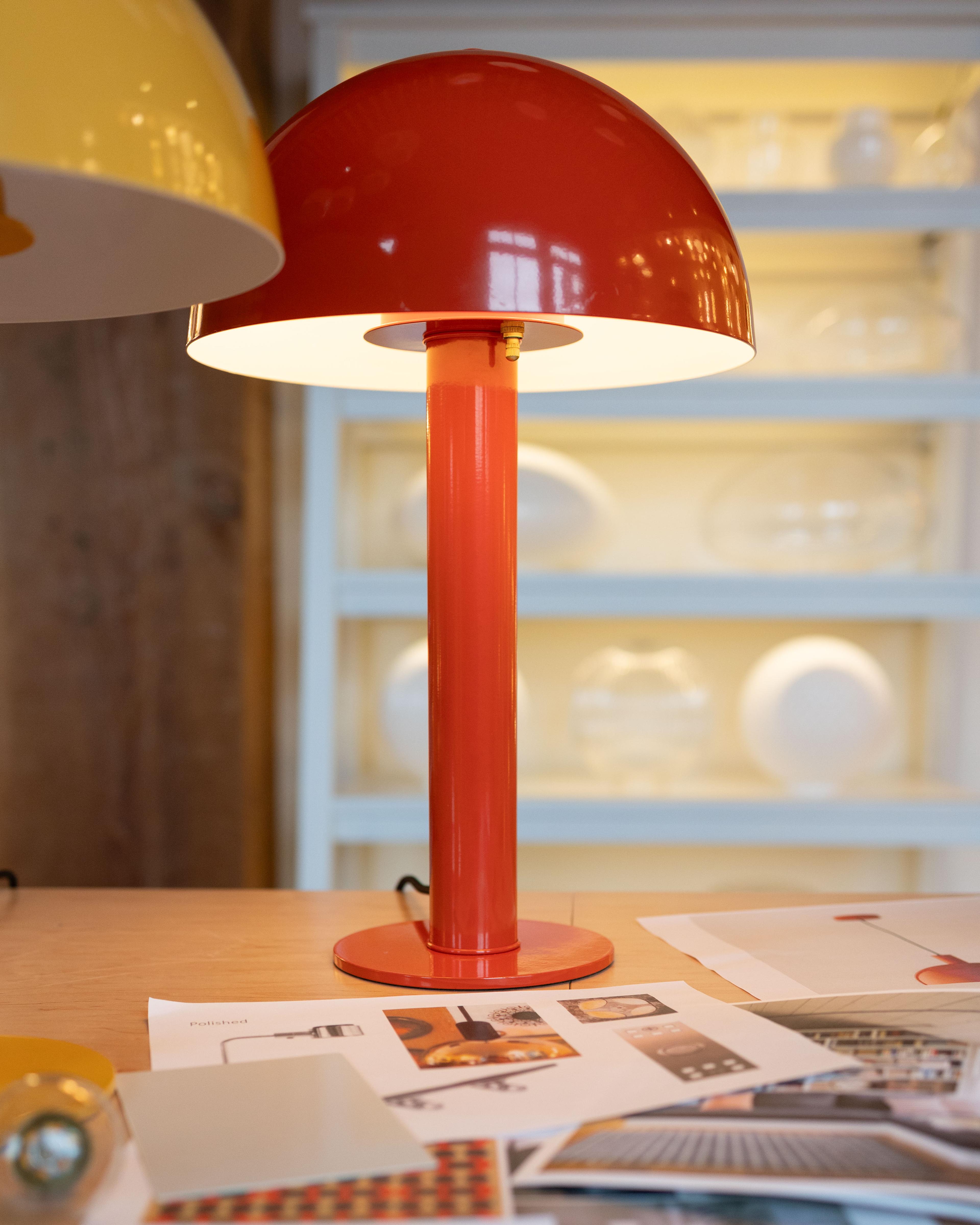 Detail shot of red mushroom table lamp on table over designs