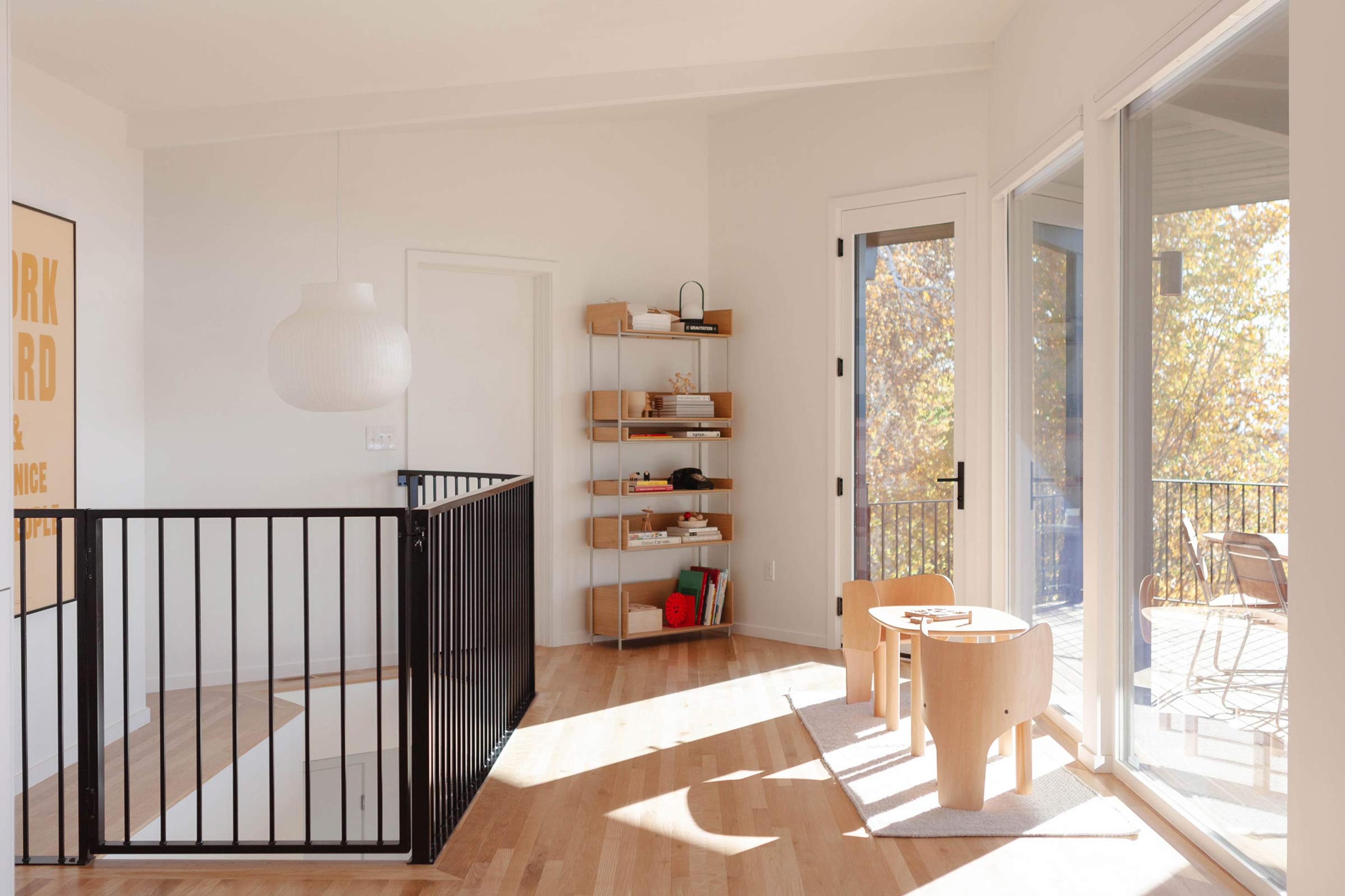 A bright living room with a pendant, bookshelf, and kid's table. 