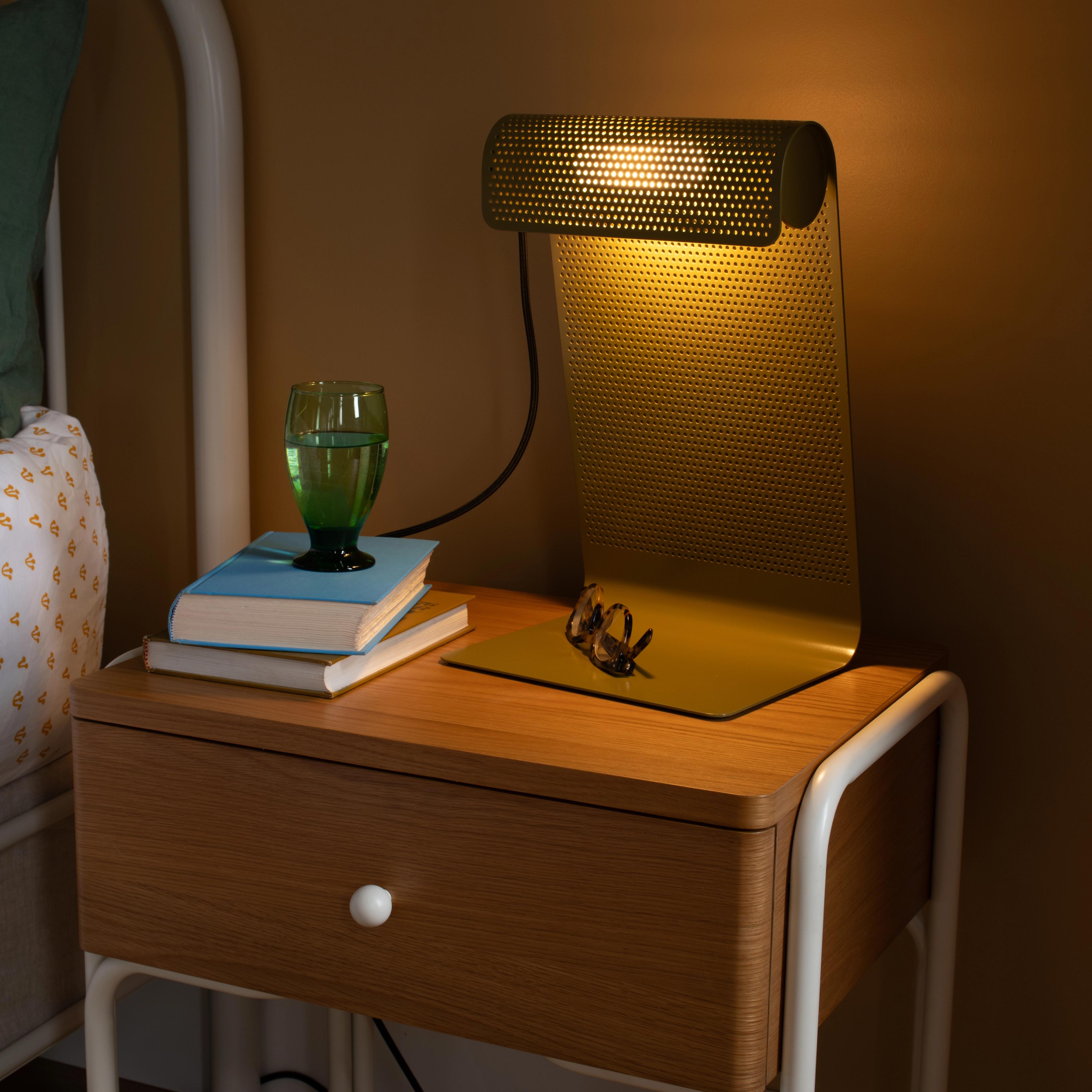 Perforated task lamp light up on wooden night stand 