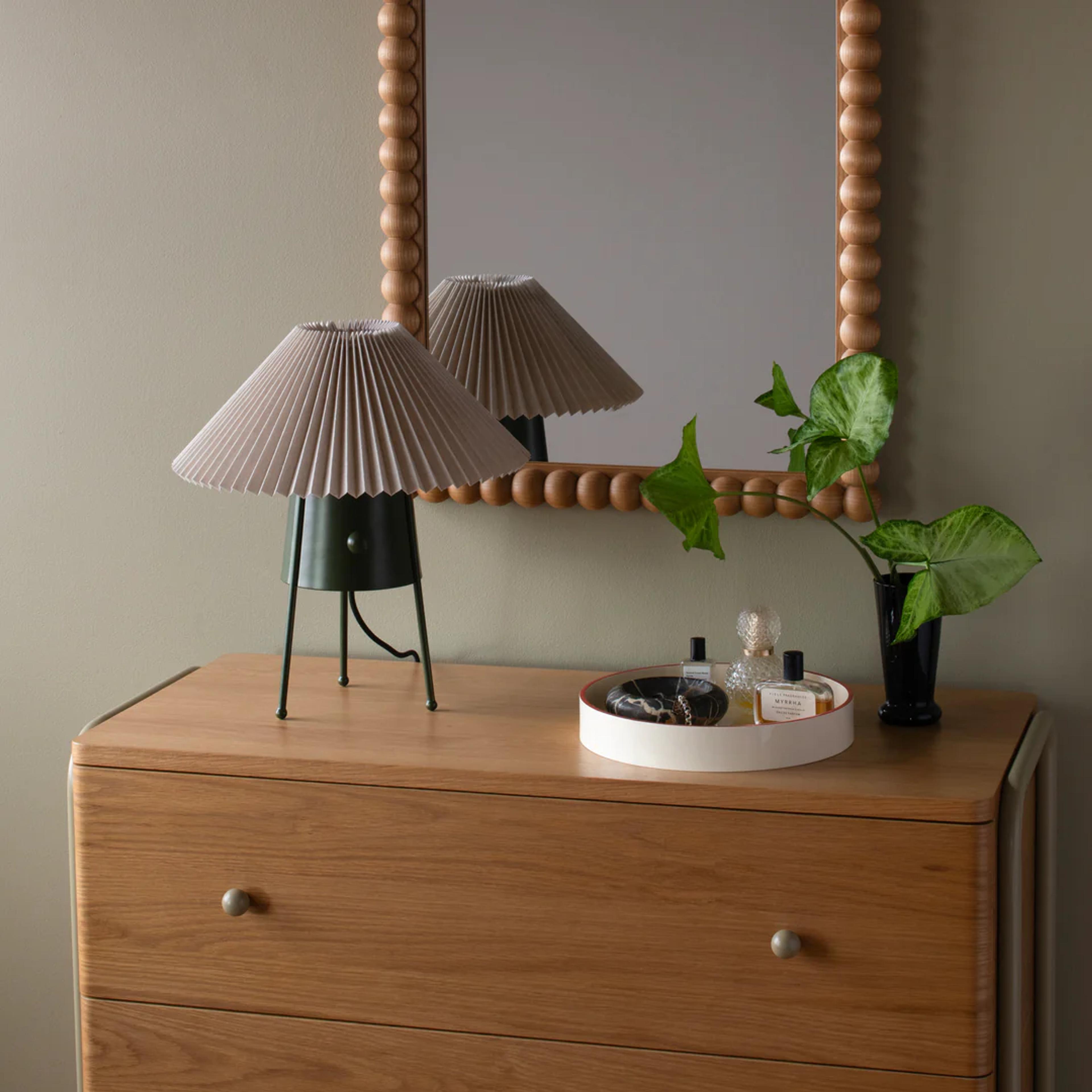Mirror above a dresser with a lamp on it.
