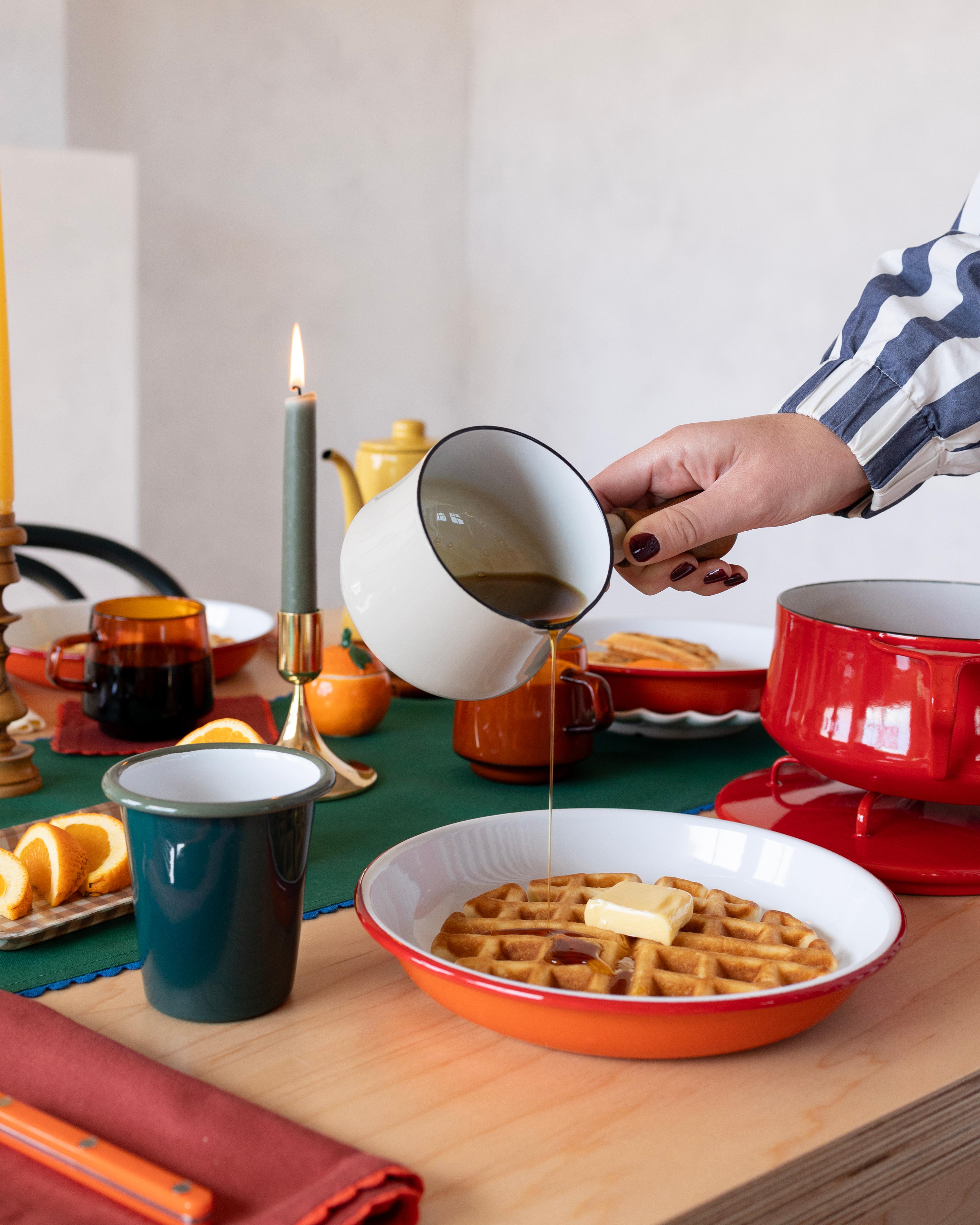 Person pouring syrup on waffles. 