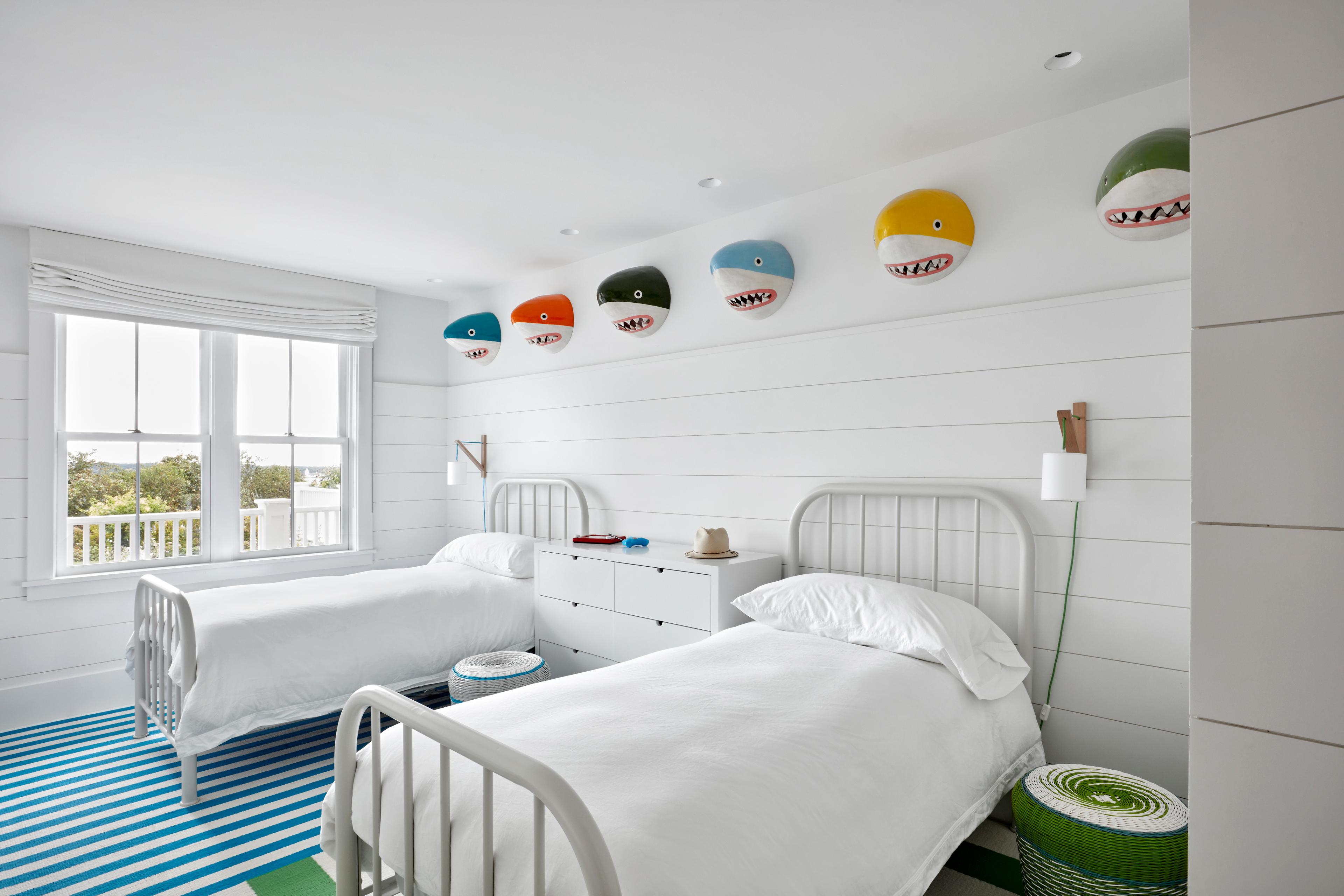 Kids room with two twin beds, shark heads above bed and striped carpet 