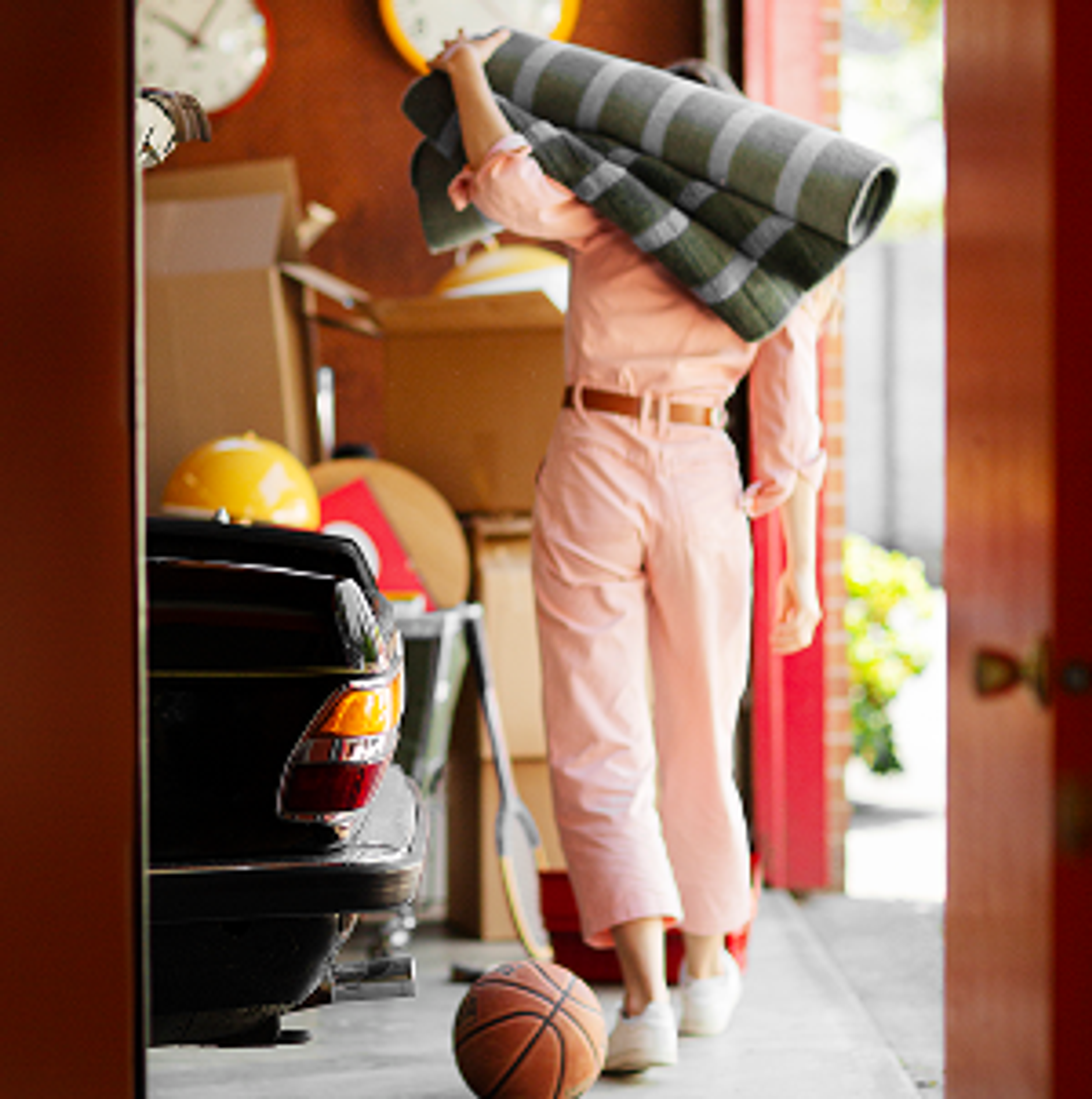 woman carrying a rug in a cluttered garage