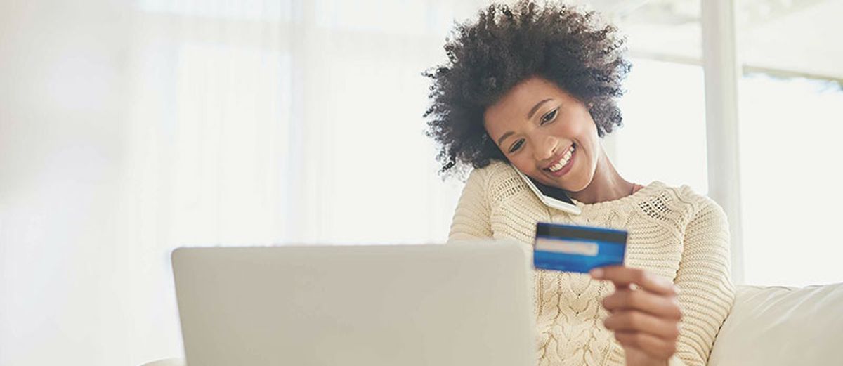 Mulher segurando um cartão de crédito e um computador