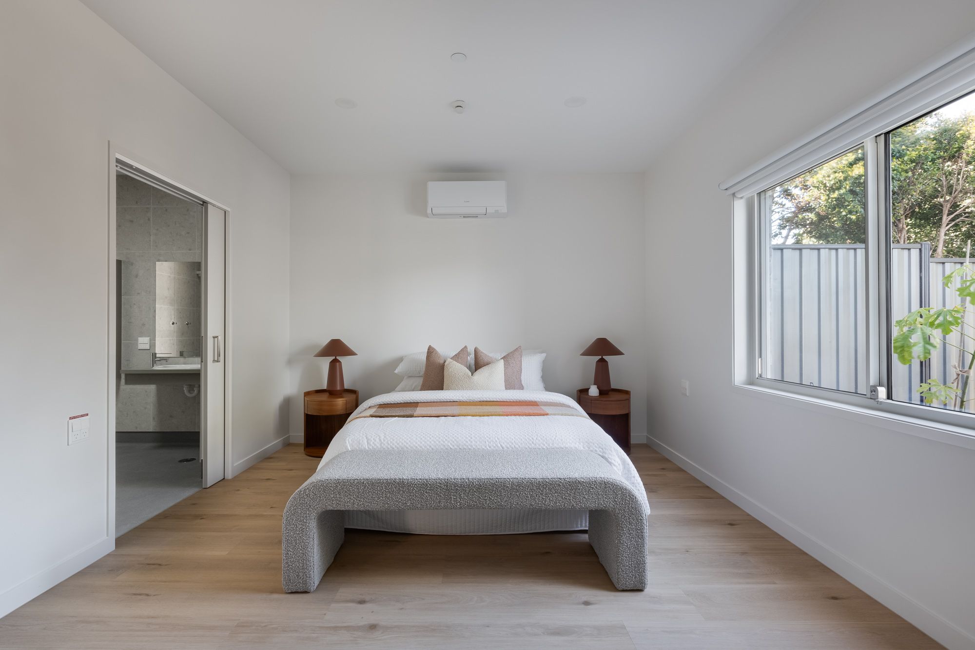 Photo of bedroom showing a bed with a lamp and bedside table on each side.