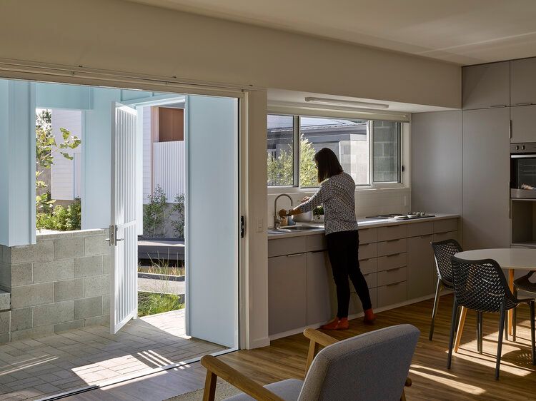 Woman standing at the kitchen sink with sunlight streaming in the window.