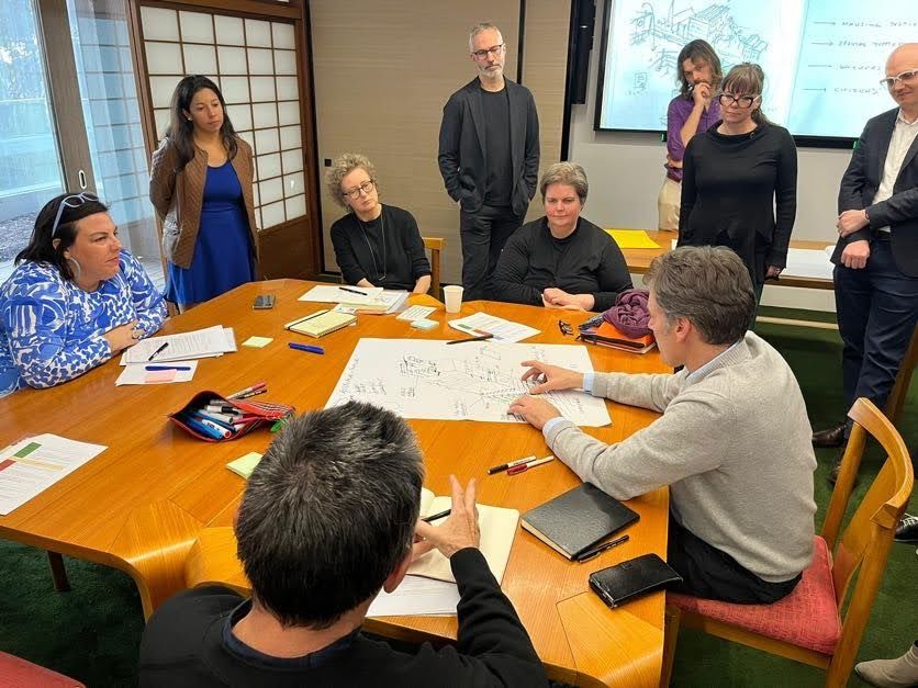 Photography of a vision group of built environment specialists at the Melbourne just transition workshop. The photograph shows a group of people sitting around a table drawing their ideas for a just transition.
