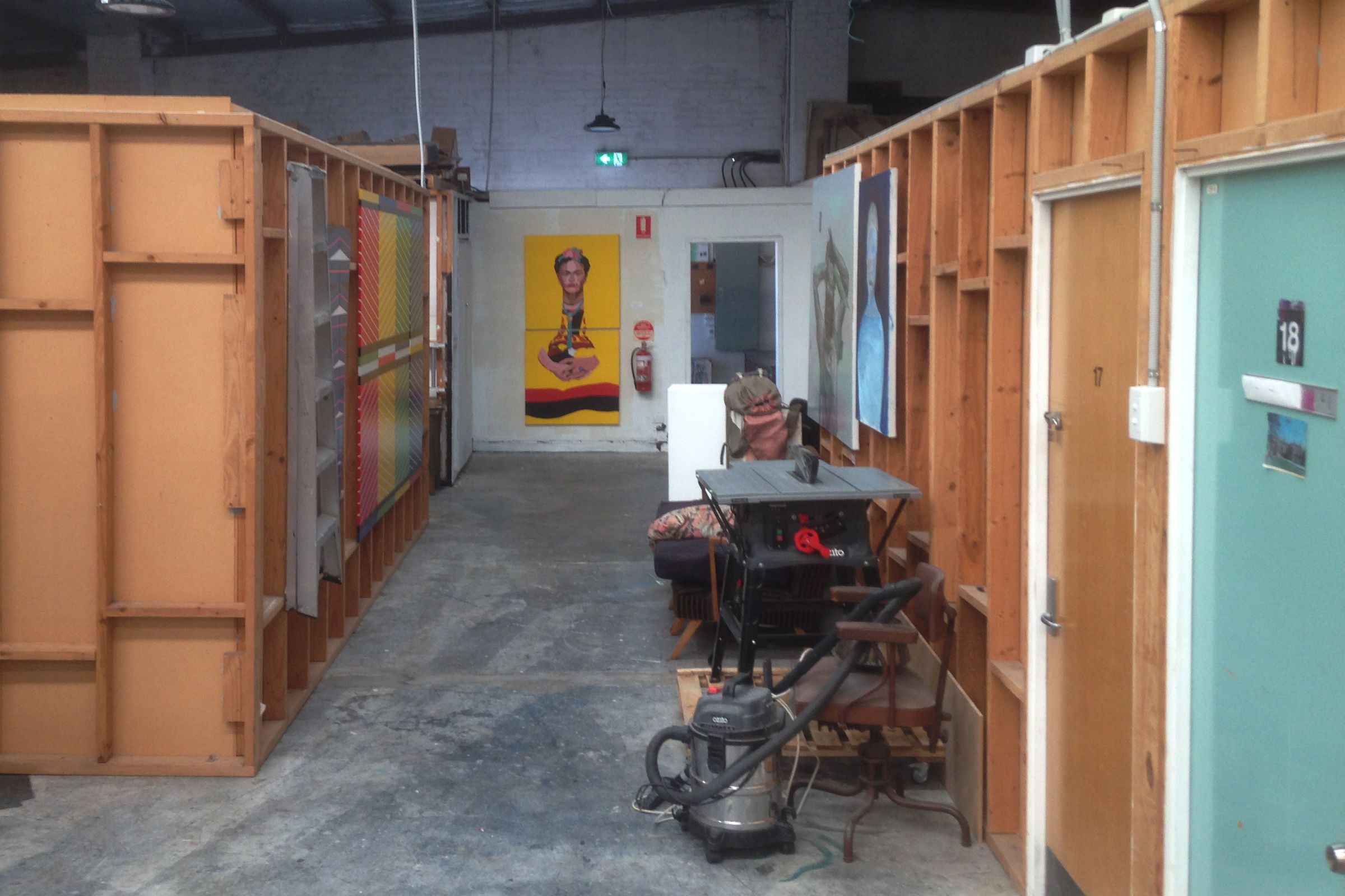 A shared warehouse space with wooden partitions creating smaller studios with different coloured doors