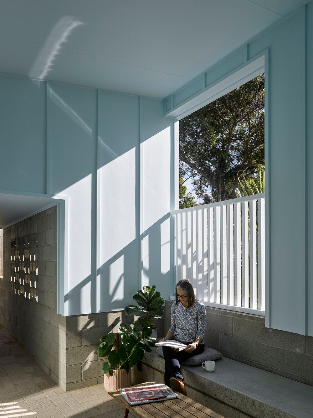 Photo of woman sitting and reading in a private outdoor space at Anne Street Garden Villas.