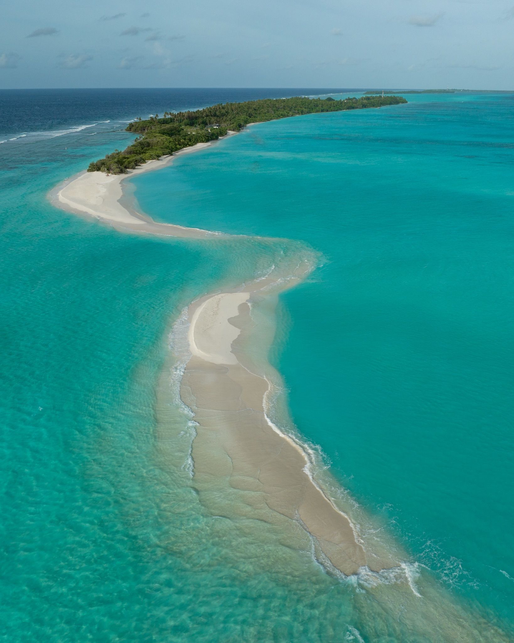 A sandbank curving into clear shallow water