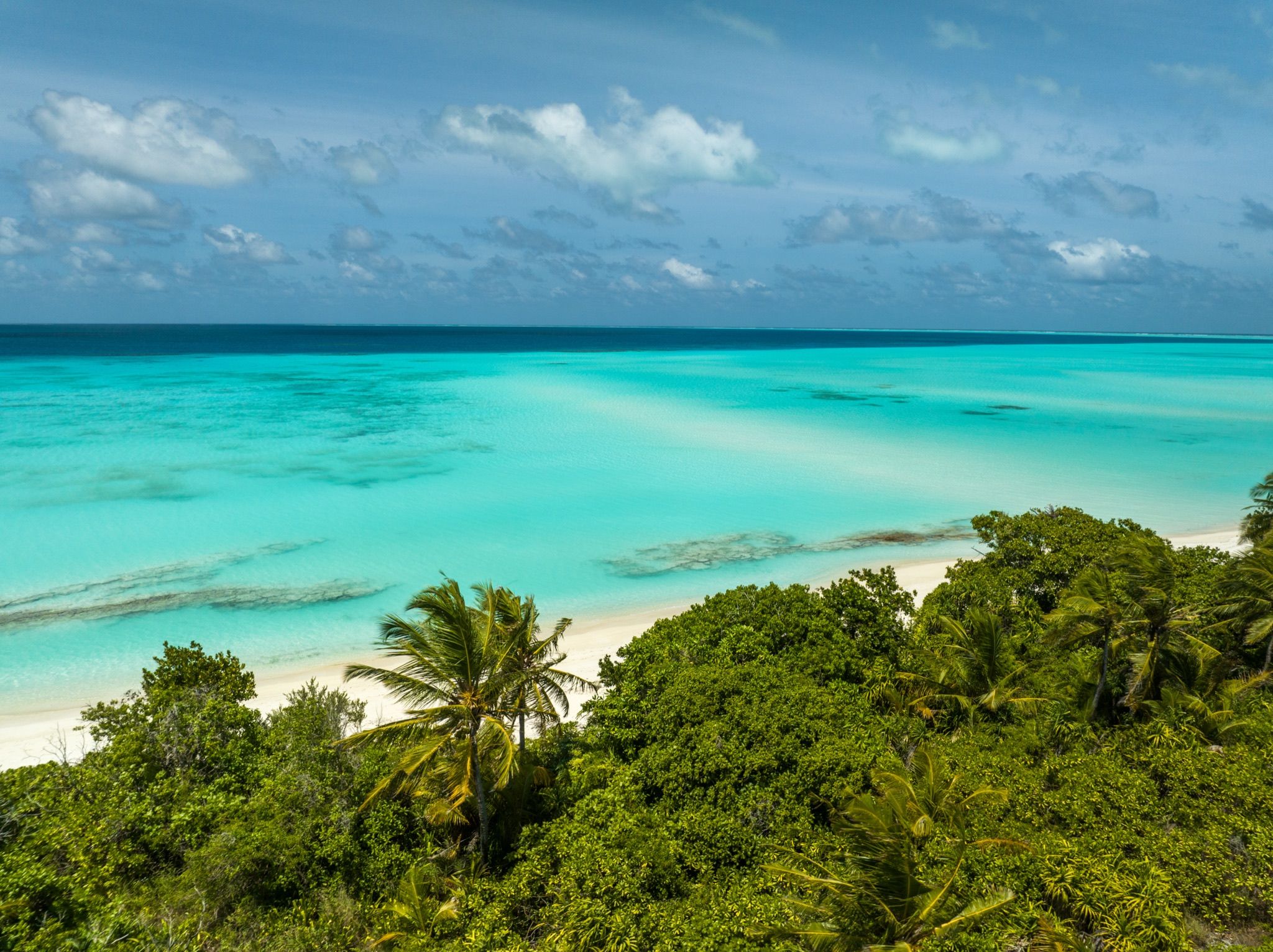 Aerial of the atoll, white sand and turquoise water to the horizon