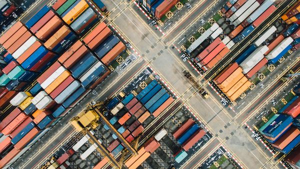 Aerial view of a busy shipping container yard, representing global trade flows affected by carbon border tariffs.