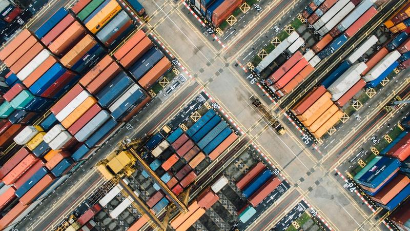 Aerial view of a busy shipping container yard, representing global trade flows affected by carbon border tariffs.