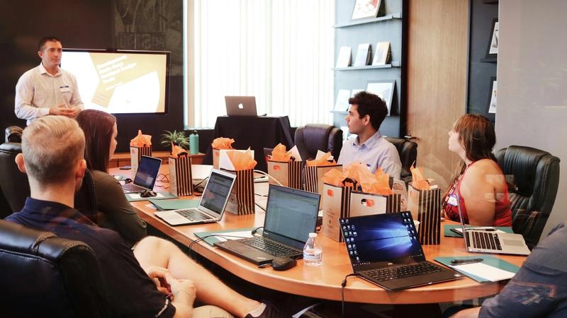 Small business team gathered around a laptop at a table, discussing plans together.