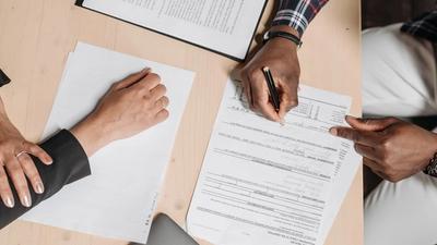 Two people reviewing and signing business documents at an office desk