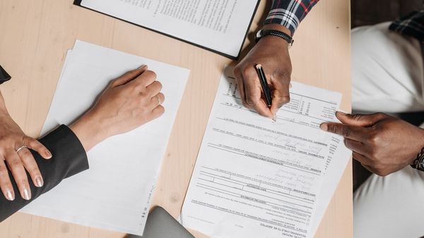 Two people reviewing and signing business documents at an office desk