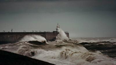 Heavy waves crashing against a sea wall during a storm, illustrating extreme weather risks the UK faces.