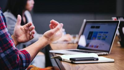 A small business team gathered around a table with laptops during a working meeting