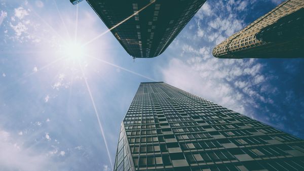 Bright summer sun blazing over glass office buildings against a blue sky