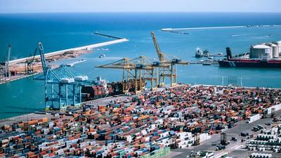 Aerial view of stacked freight shipping containers at a port terminal, representing imported goods subject to the UK Carbon Border Adjustment Mechanism