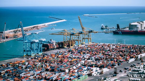 Aerial view of stacked freight shipping containers at a port terminal, representing imported goods subject to the UK Carbon Border Adjustment Mechanism