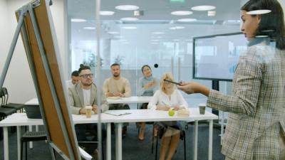 A presenter delivering training to an attentive group of colleagues in a modern office, illustrating organisation-wide workplace learning.