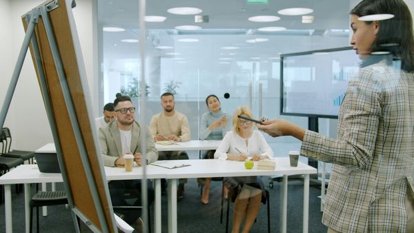 A presenter delivering training to an attentive group of colleagues in a modern office, illustrating organisation-wide workplace learning.