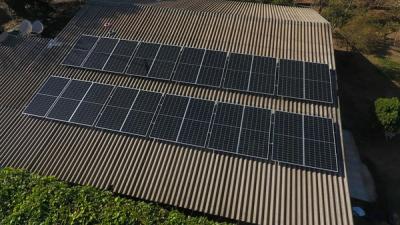 Rows of solar panels installed across the corrugated metal roof of a commercial building, seen from above