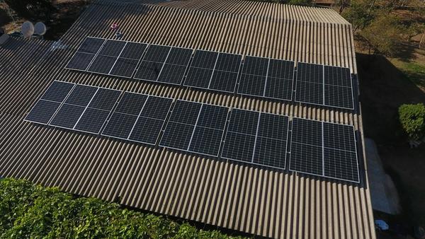 Rows of solar panels installed across the corrugated metal roof of a commercial building, seen from above