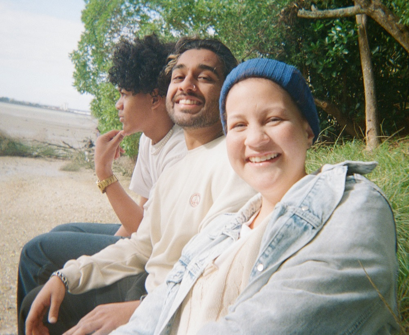 a woman wearing a blue beanie smiles with two other people