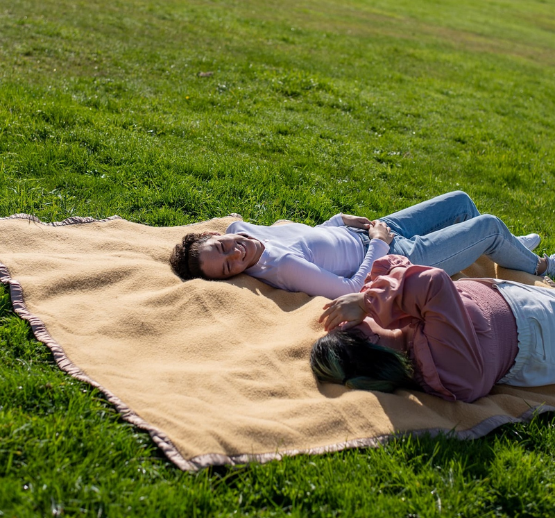 two people laying on a blanket in the grass