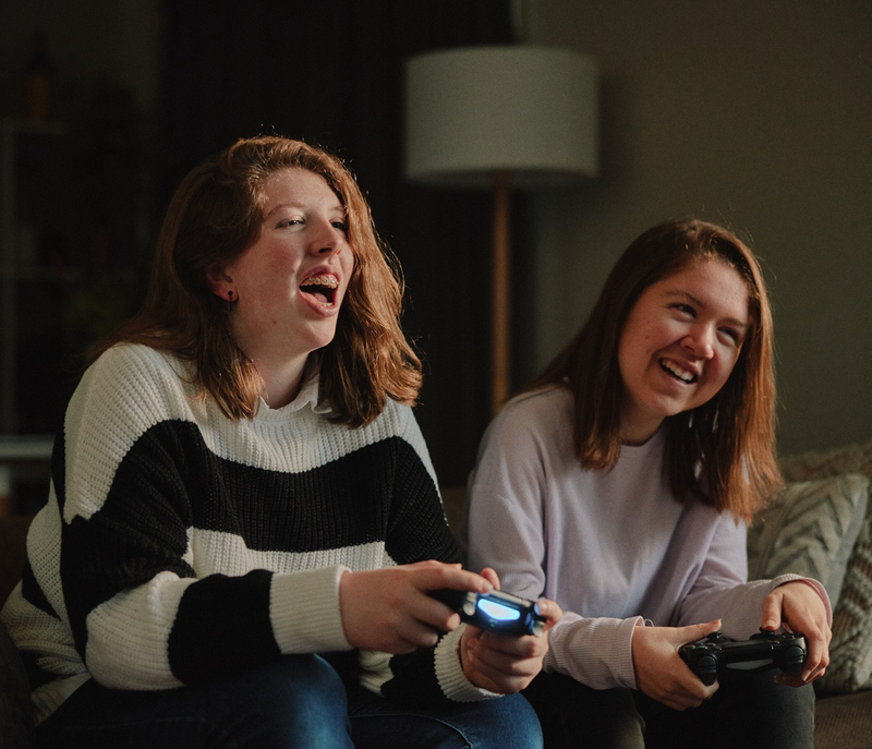 two girls are sitting on a couch playing a video game