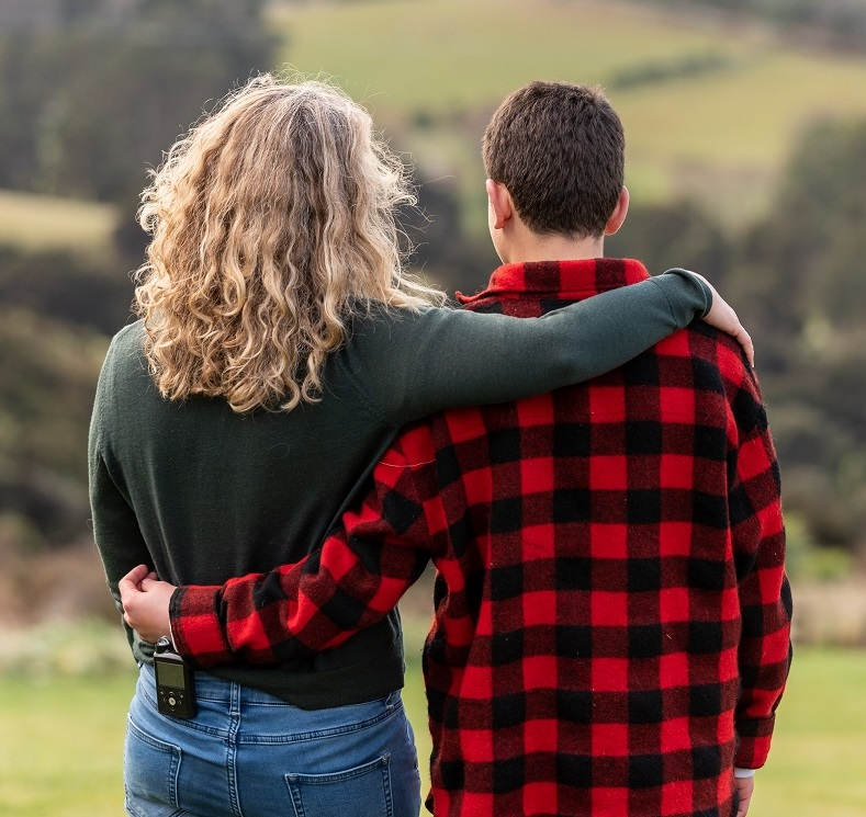 a man in a plaid shirt has his arm around a woman 's shoulder