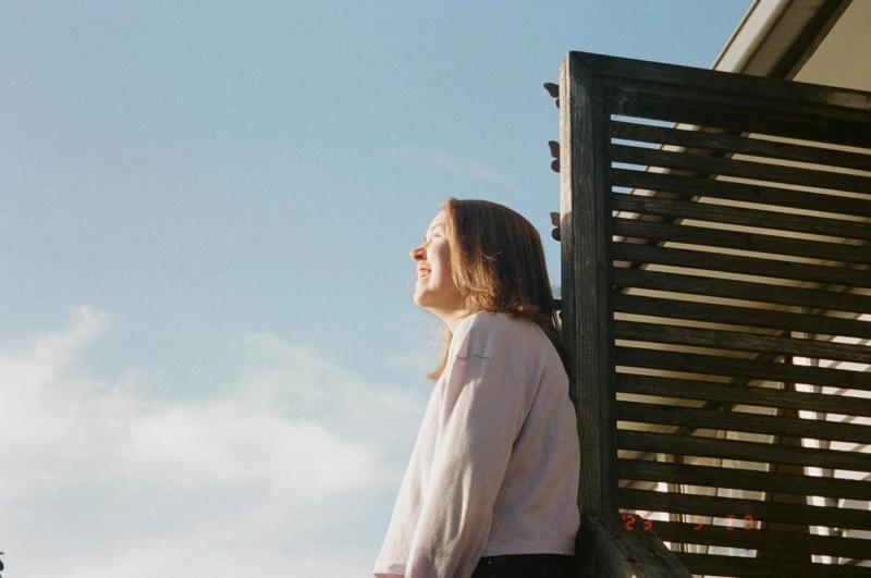 a woman is standing on a balcony looking up at the sky .