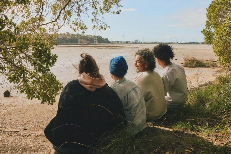 a group of people are sitting on the grass near a body of water .
