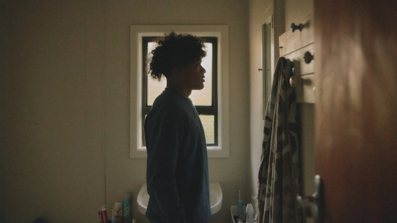 a person standing in a bathroom looking out a window a person standing in a bathroom looking out a window